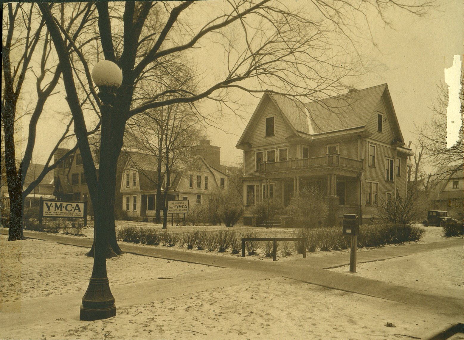 The two frame houses at Wright and Chalmers that served as the Y's headquarters from 1928 to 1937, with the Y.M.C.A. sign on the corner lawn. University YMCA archives.