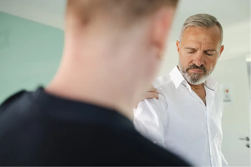 Massør undersøger medarbejders skulderbevægelighed under forberedelse til massage på arbejdspladsen.