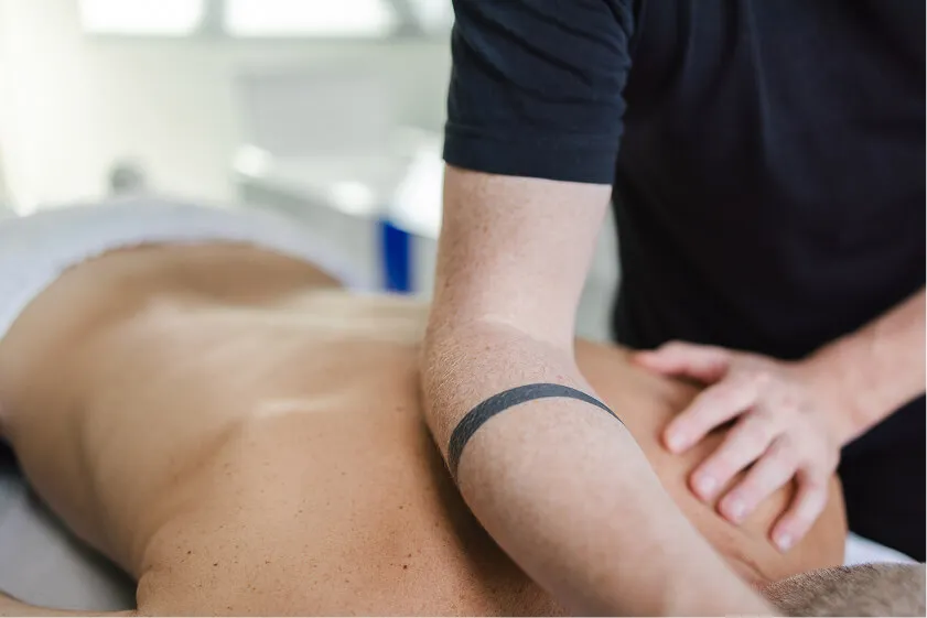 Massør udfører dybdemassage på medarbejders ryg for at løsne spændinger og øge velvære.