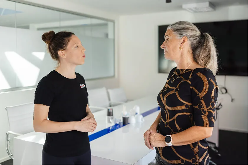 Massør og medarbejder taler sammen i mødelokale om behov og effekt af firmamassage.