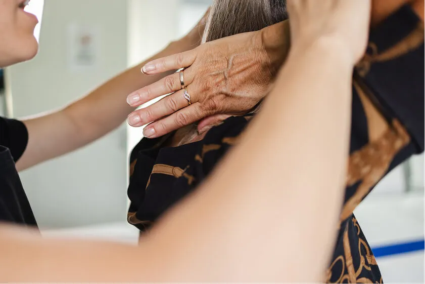 Massør hjælper medarbejder med stræk af nakke og skuldre for at løsne spændinger.