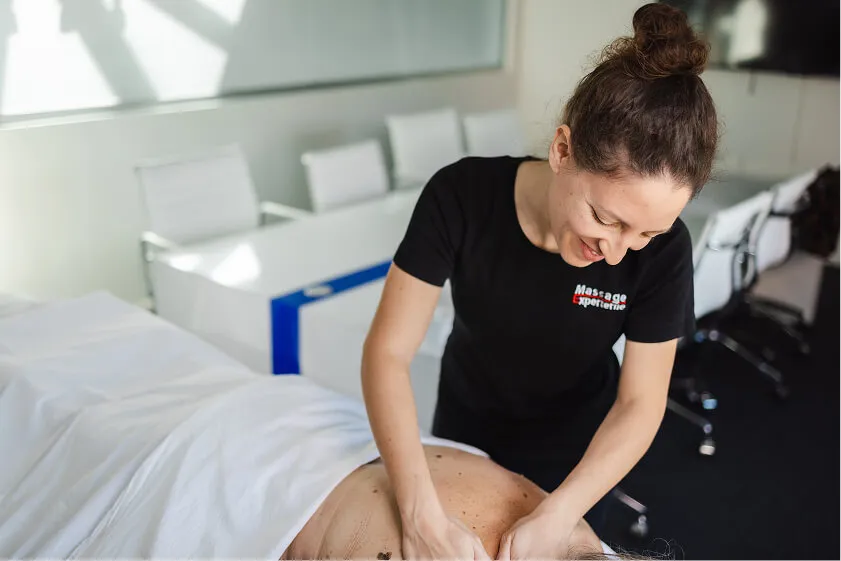 Massør fra Massage Experterne giver rygmassage i lyst kontormiljø som del af firmamassageordning.