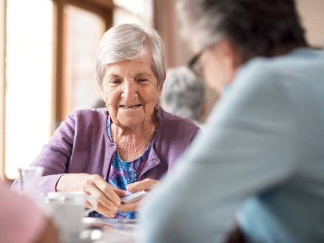 Seniorin spielt Karten in einer Tagespflege-Einrichtung