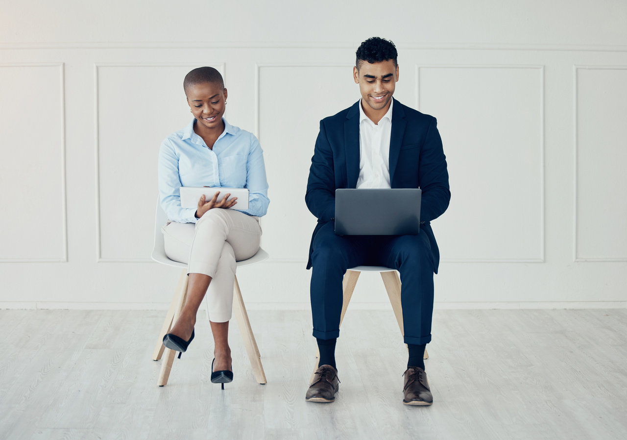 a business woman and man sitting and dealing with their digital devices to test