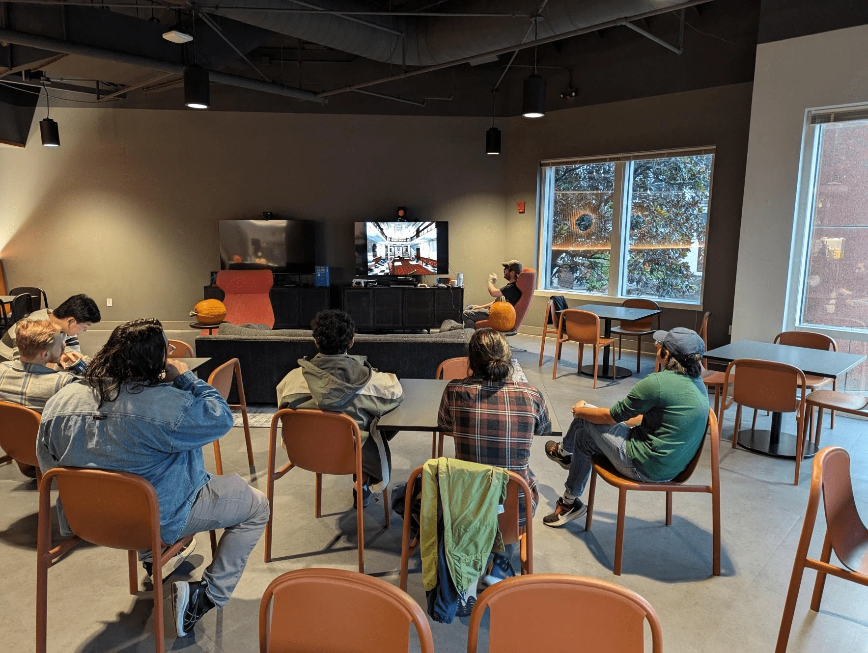 Members of Iron Galaxy Nashville gathered around tables in chairs watch Josh play Resident Evil