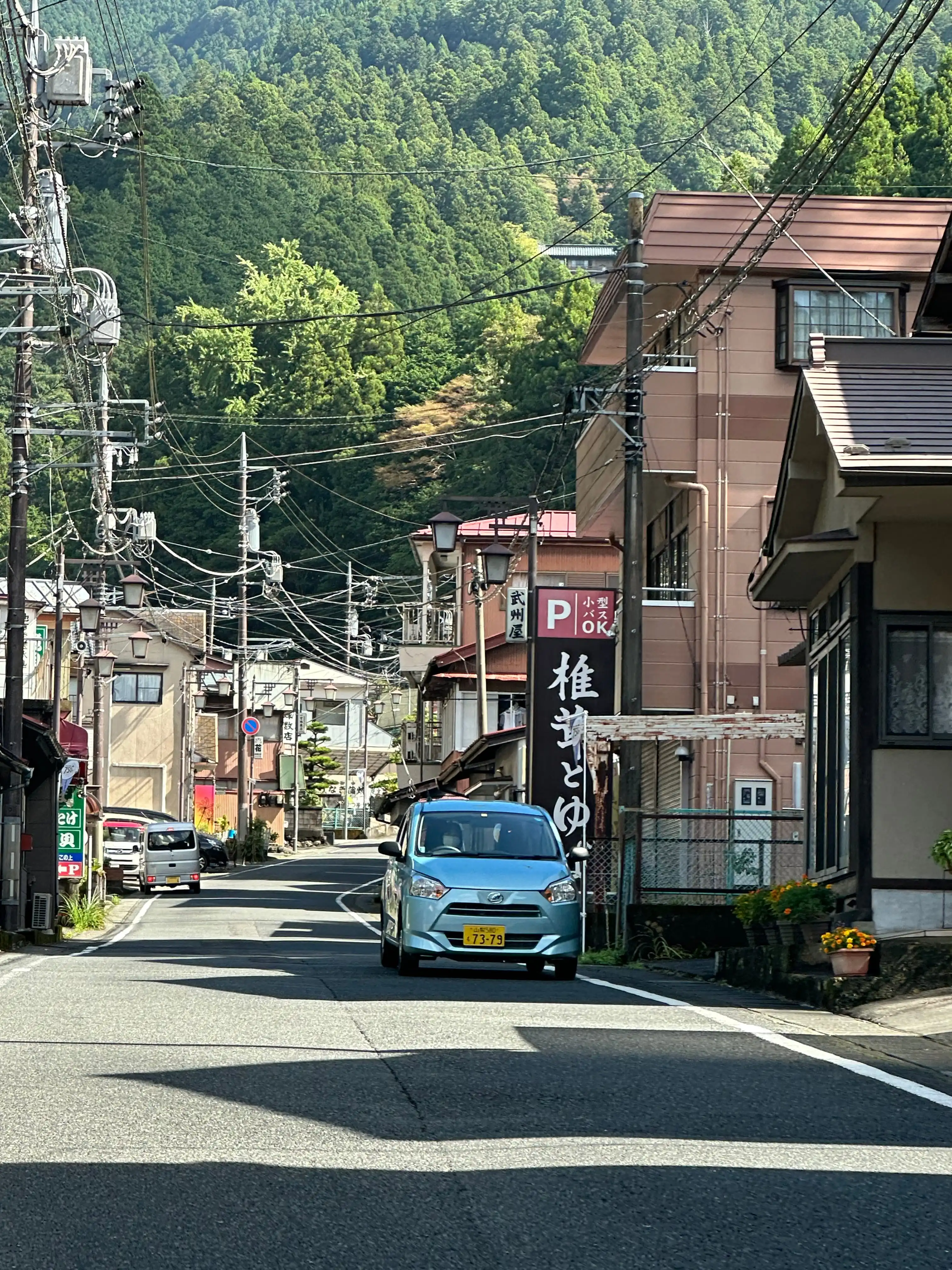 A picture looking down a street in Japan, surrounded by buildings with trees in the background