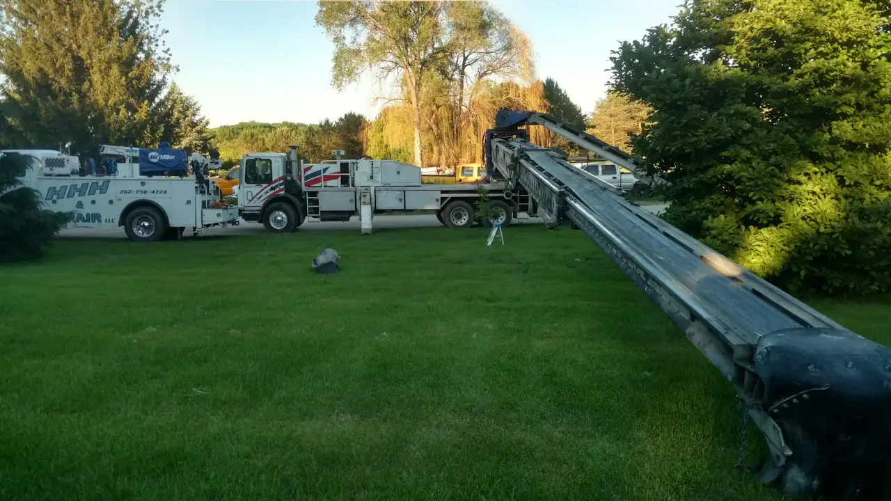 Scheduled Mobile truck repair Scheduled mobile truck repair with a boom truck extended across a lawn beside an HHH Air, LLC service vehicle.
