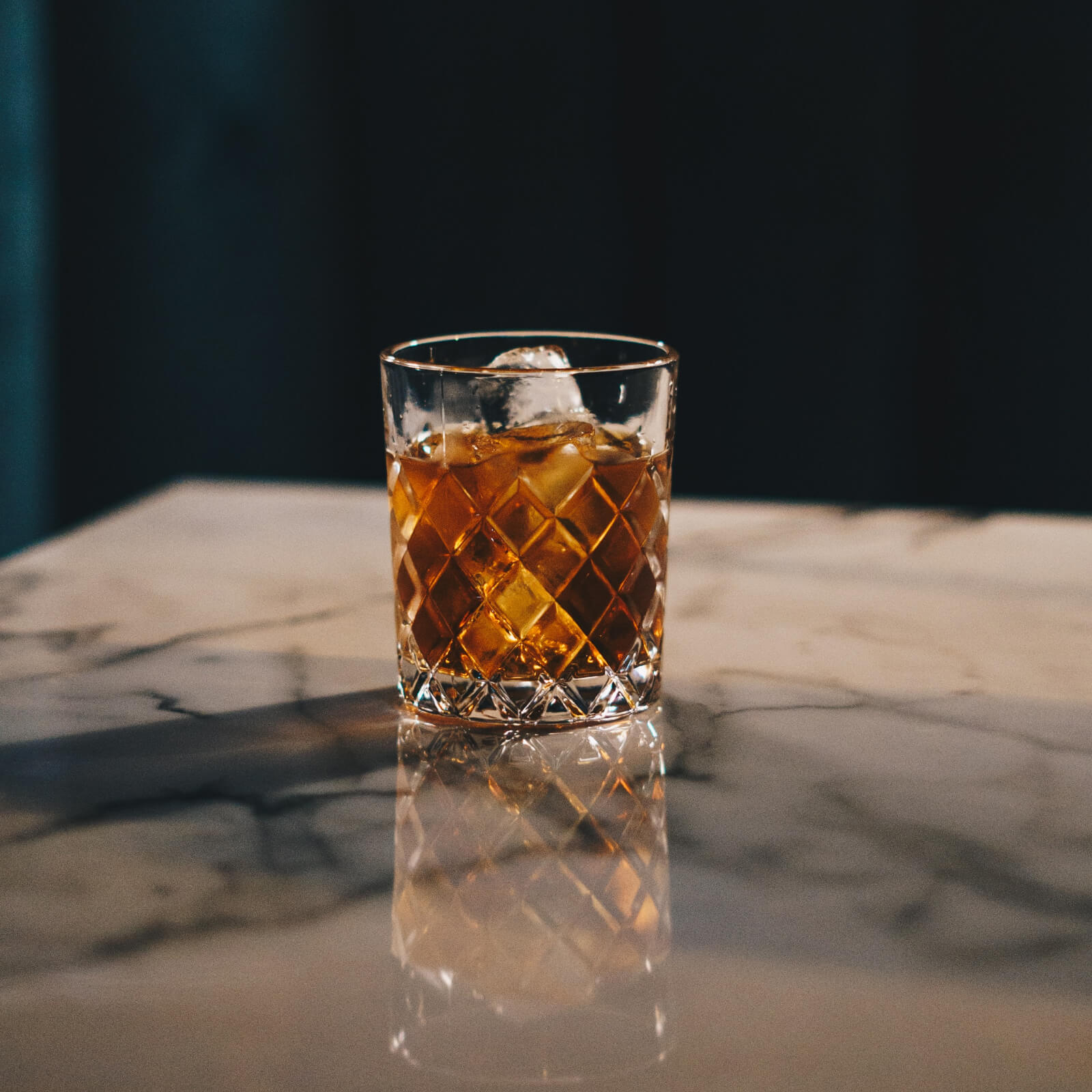 A photo of a whisky glass on a marble table.