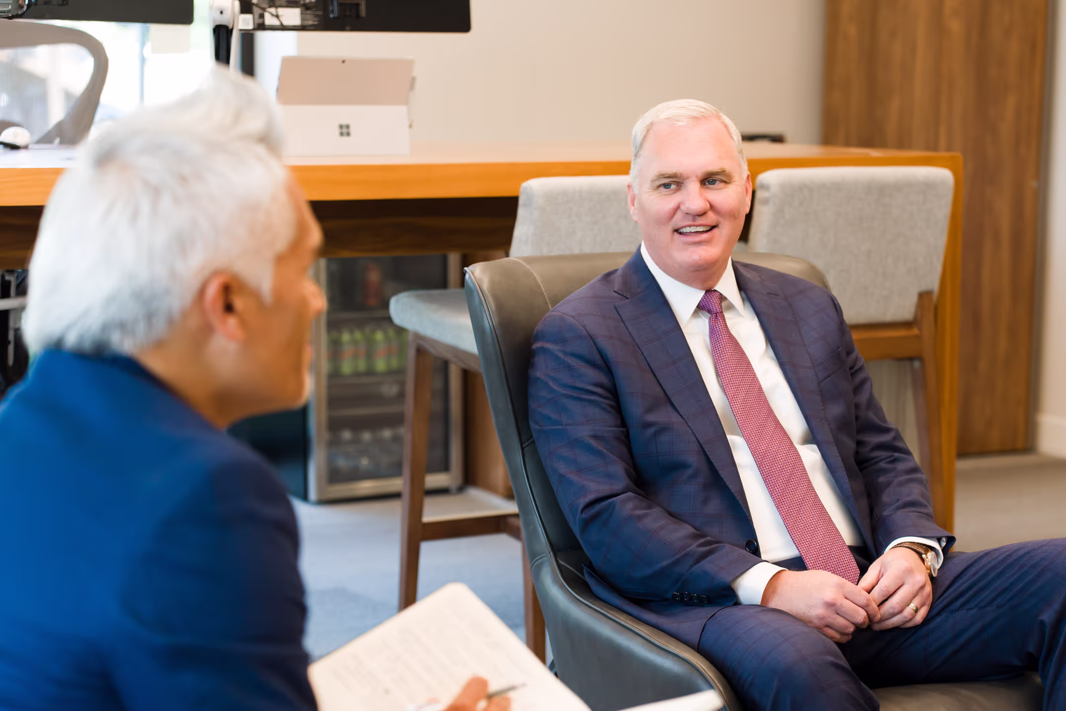 Two business men smiling while speaking in an office