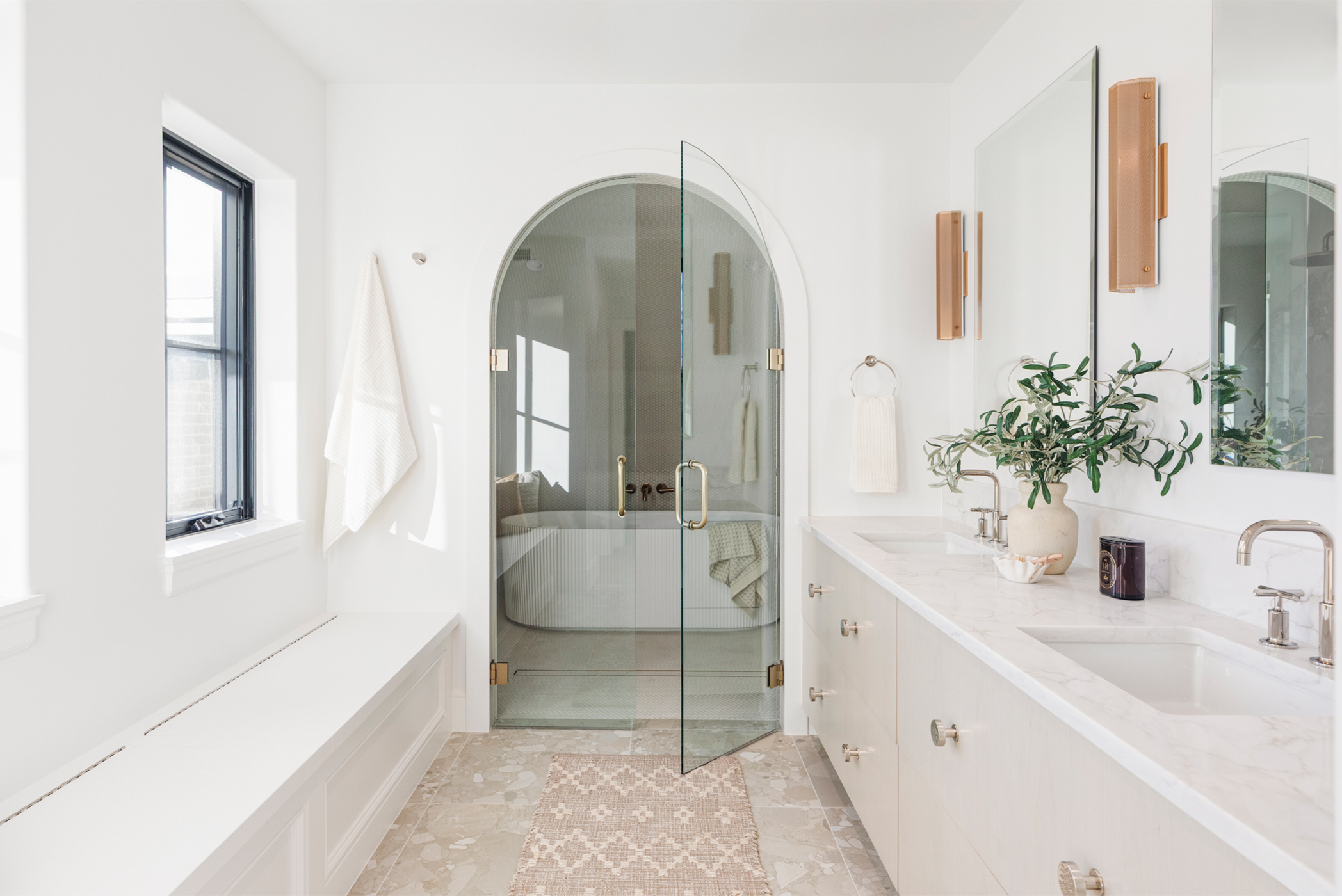 Bright primary bathroom with double vanity and arched doorway leading to walk-in shower.