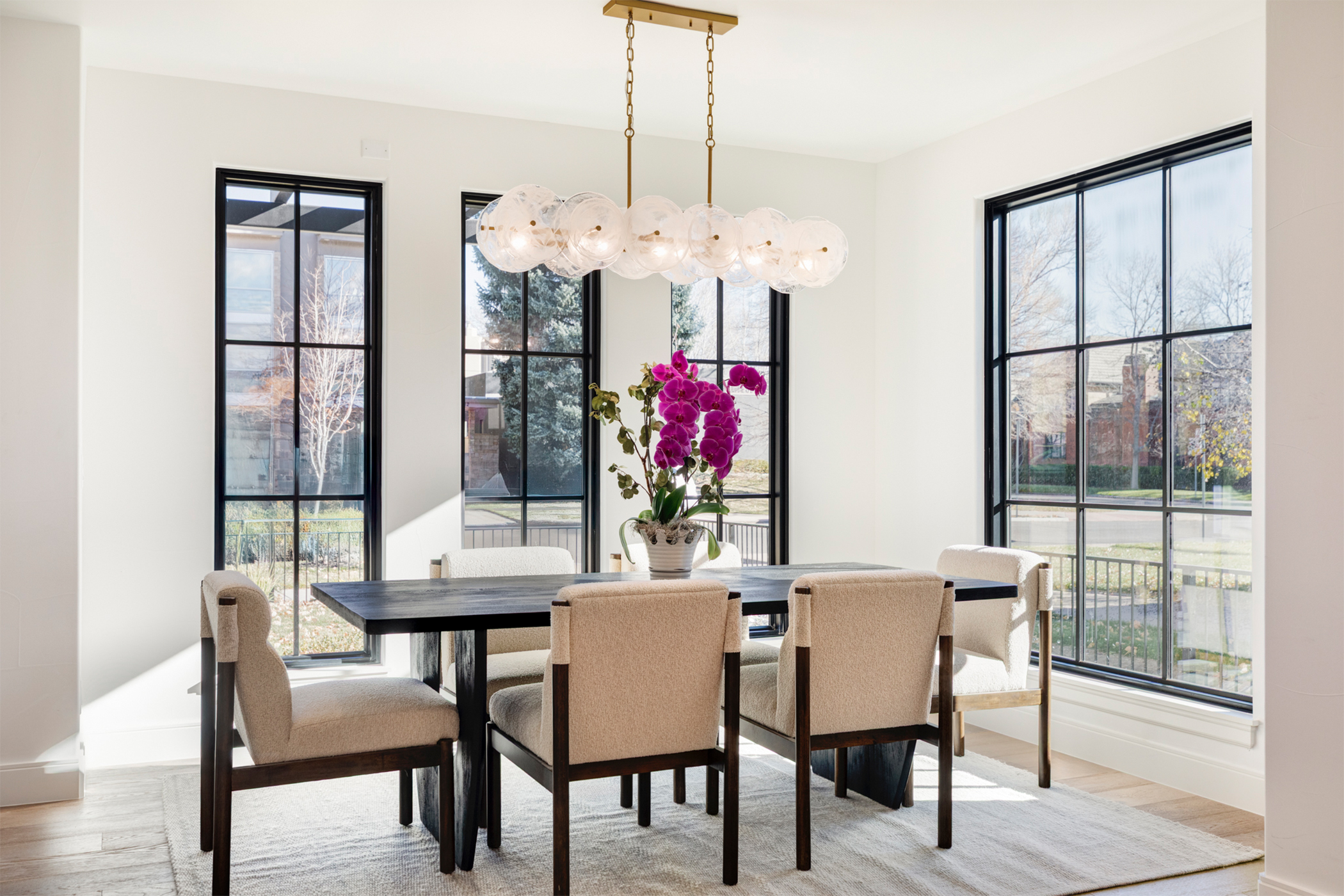 Dining area with large windows, modern chandelier, and open-concept layout.