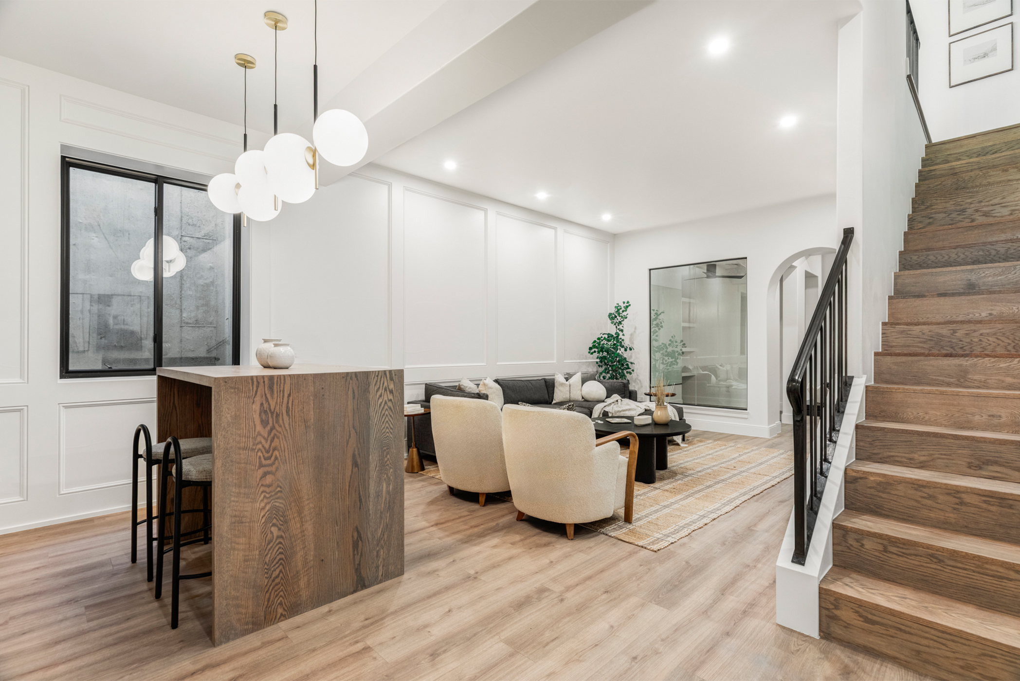 Open-concept main floor with modern kitchen island, dining space, and staircase detail.