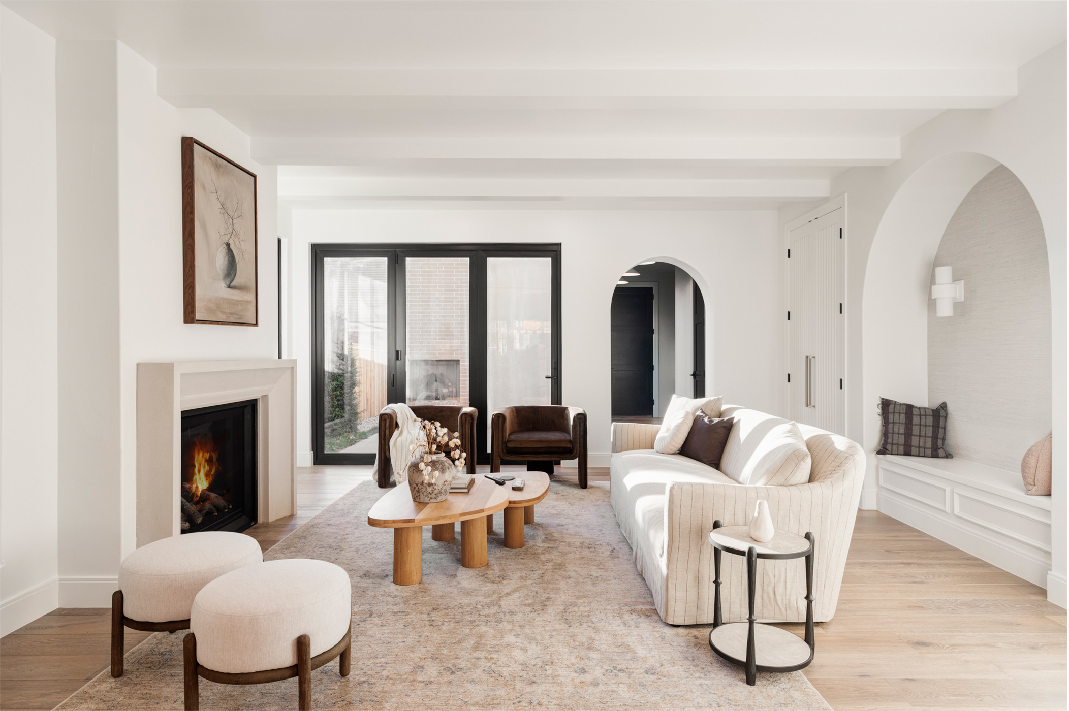 Modern sitting area with fireplace, arched openings, and soft neutral finishes.