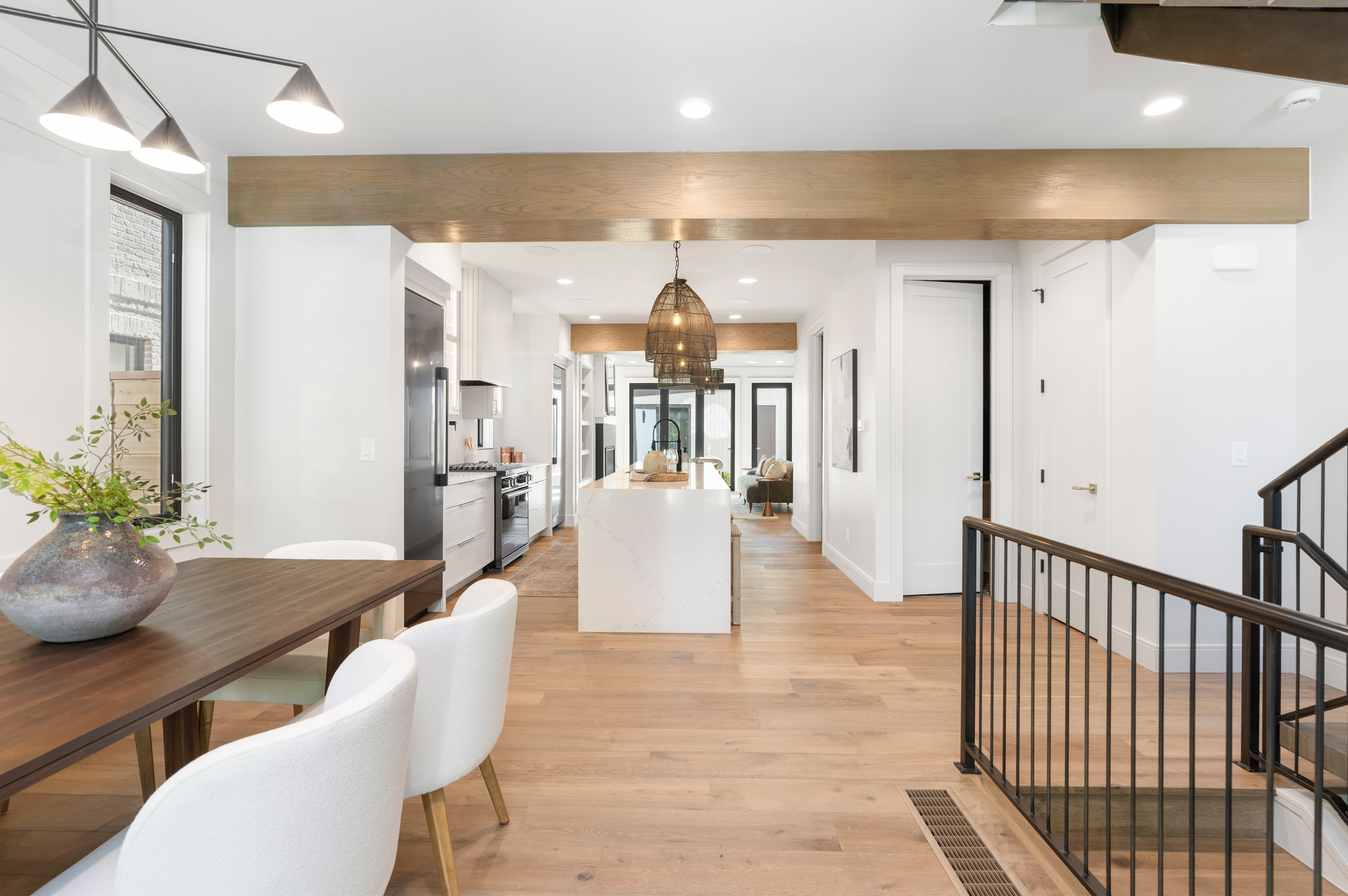 Open-concept main floor with warm wood flooring and contemporary beam ceiling.