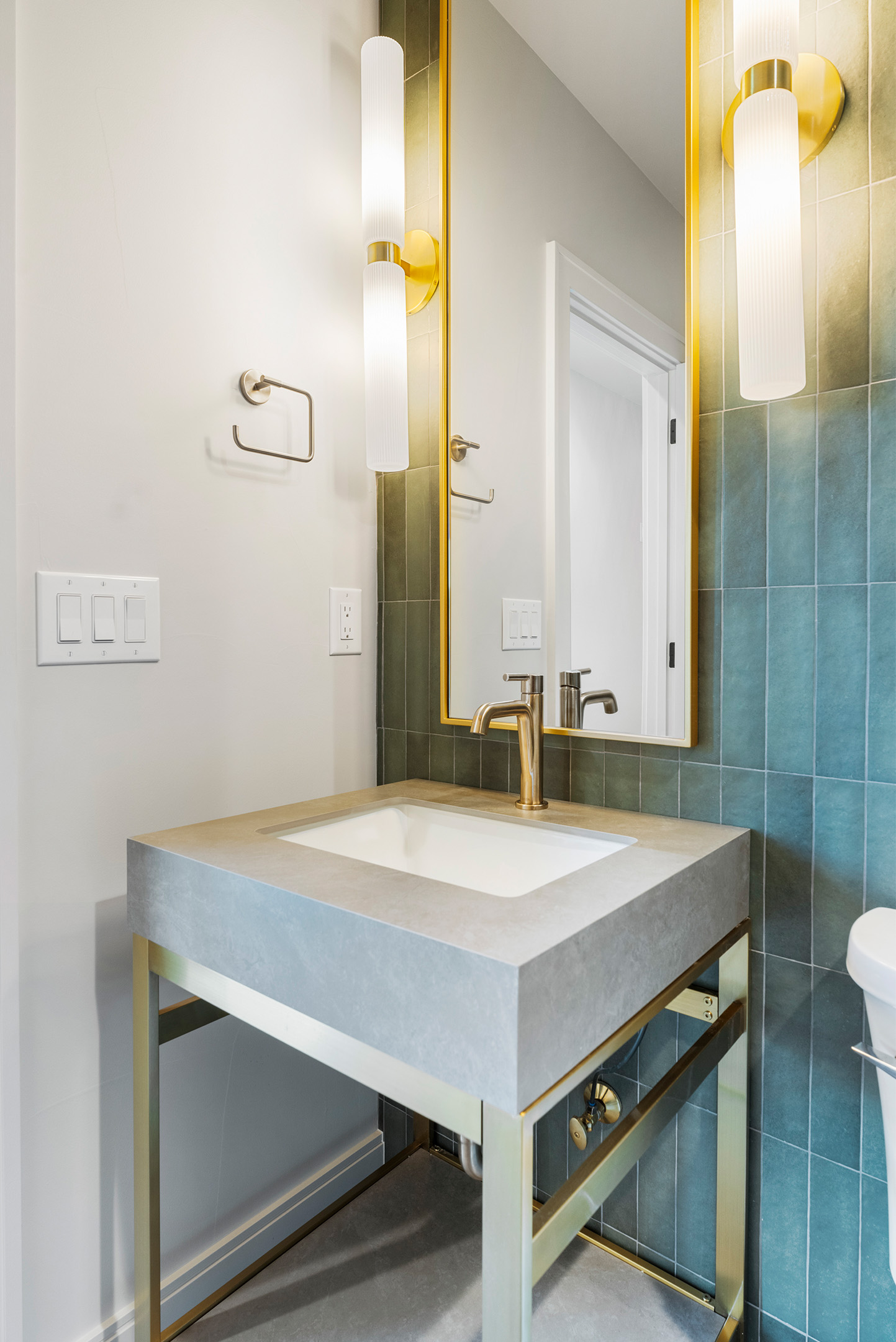 Stylish powder bathroom with modern console sink and brass mirror accents.
