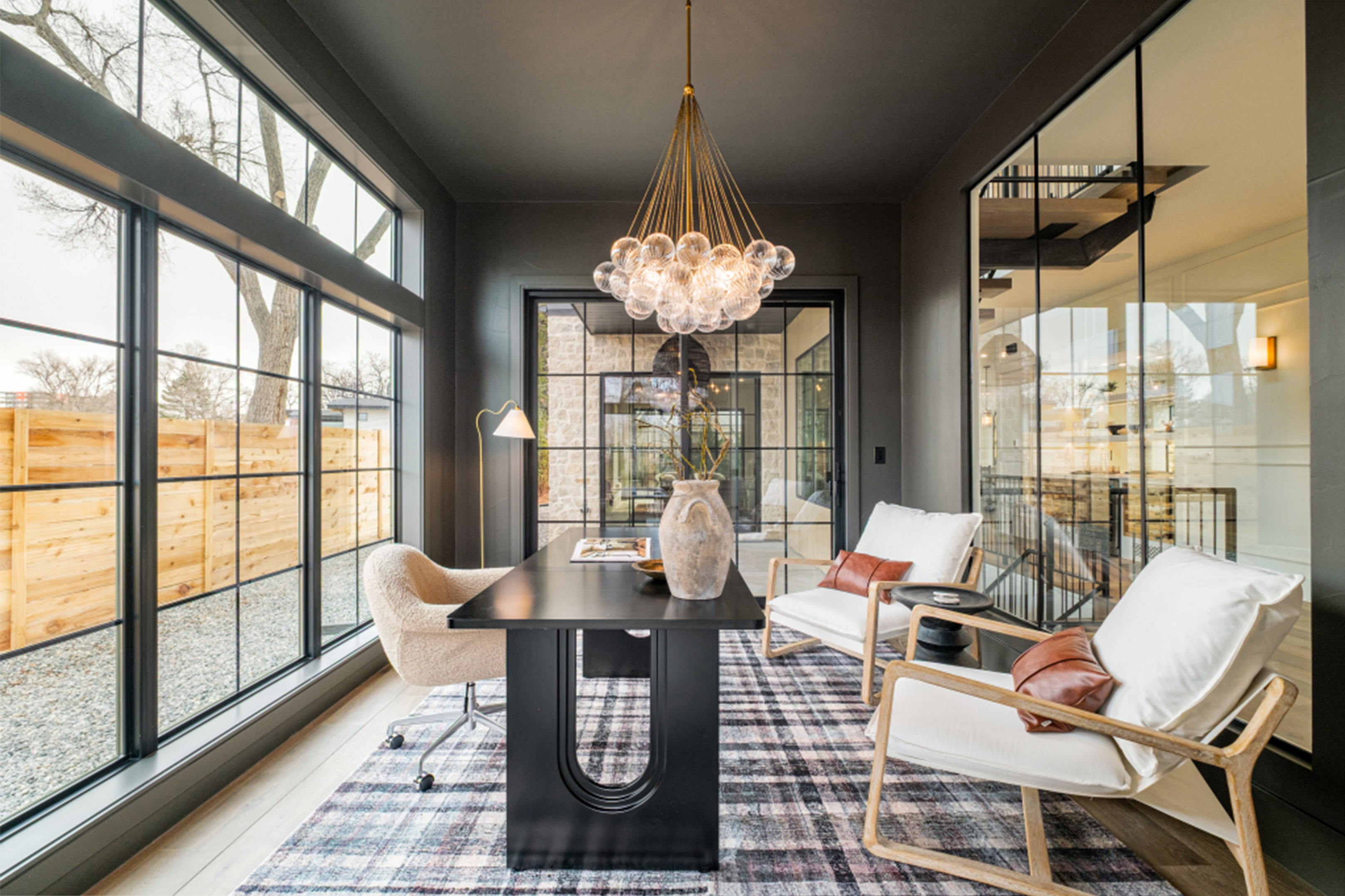 Sunlit lounge area with chandelier, modern seating, and expansive glass doors.