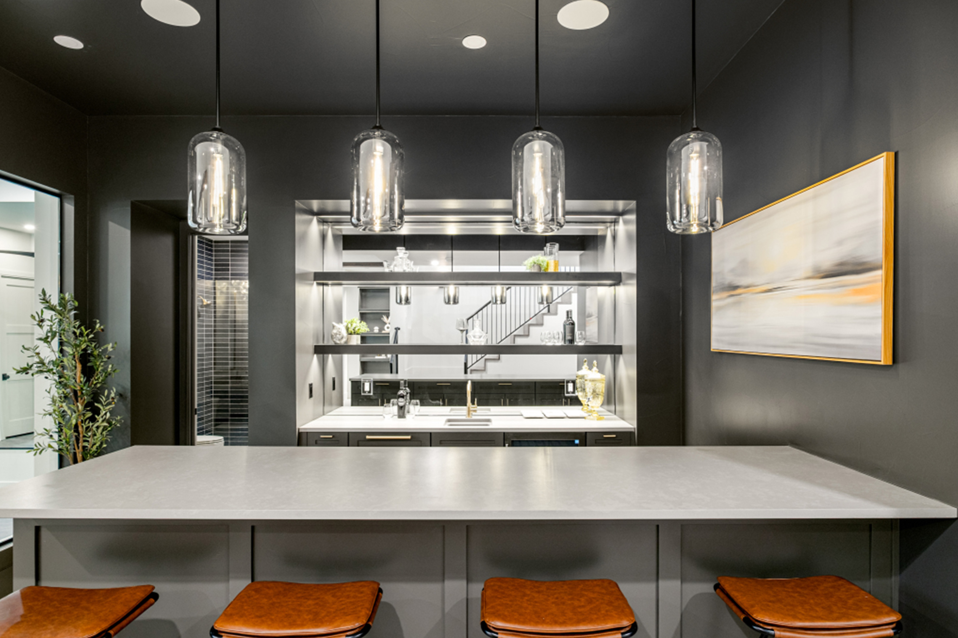 Modern wet bar with dark cabinetry, open shelving, and pendant lighting.