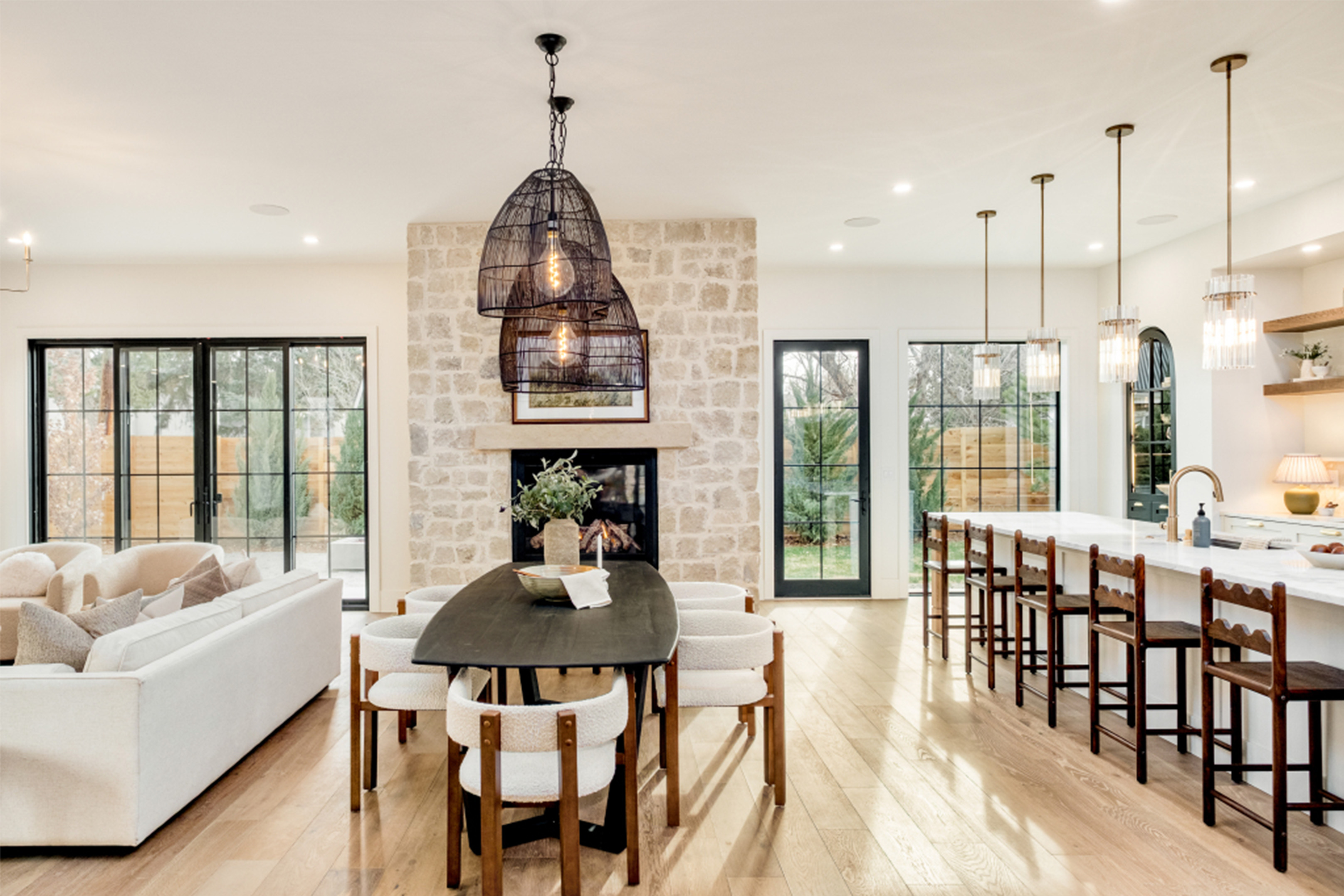 Open-concept dining and living space with oversized island and designer lighting.