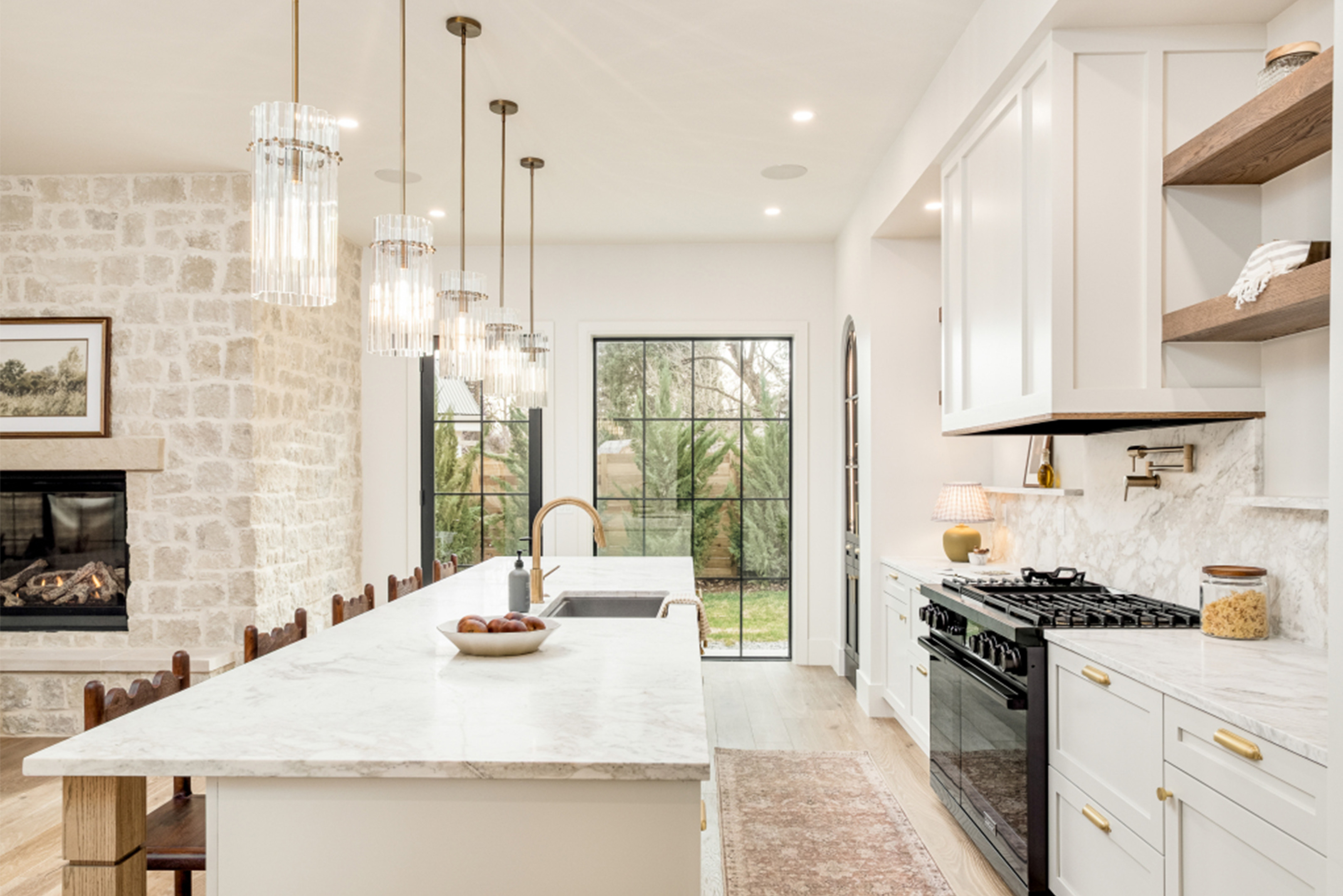 Luxury kitchen with waterfall island, brass fixtures, and bright open layout.
