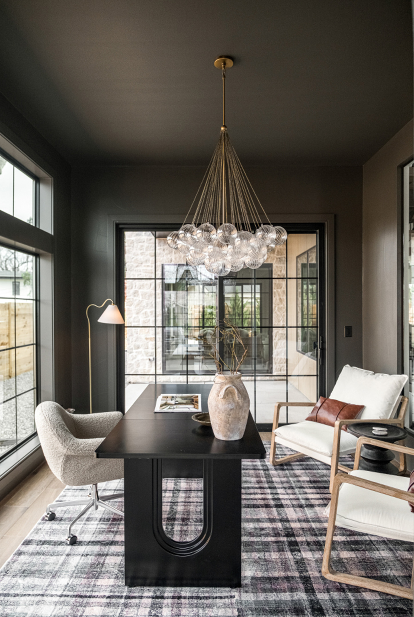 Moody sitting area with dramatic chandelier and floor-to-ceiling glass doors.