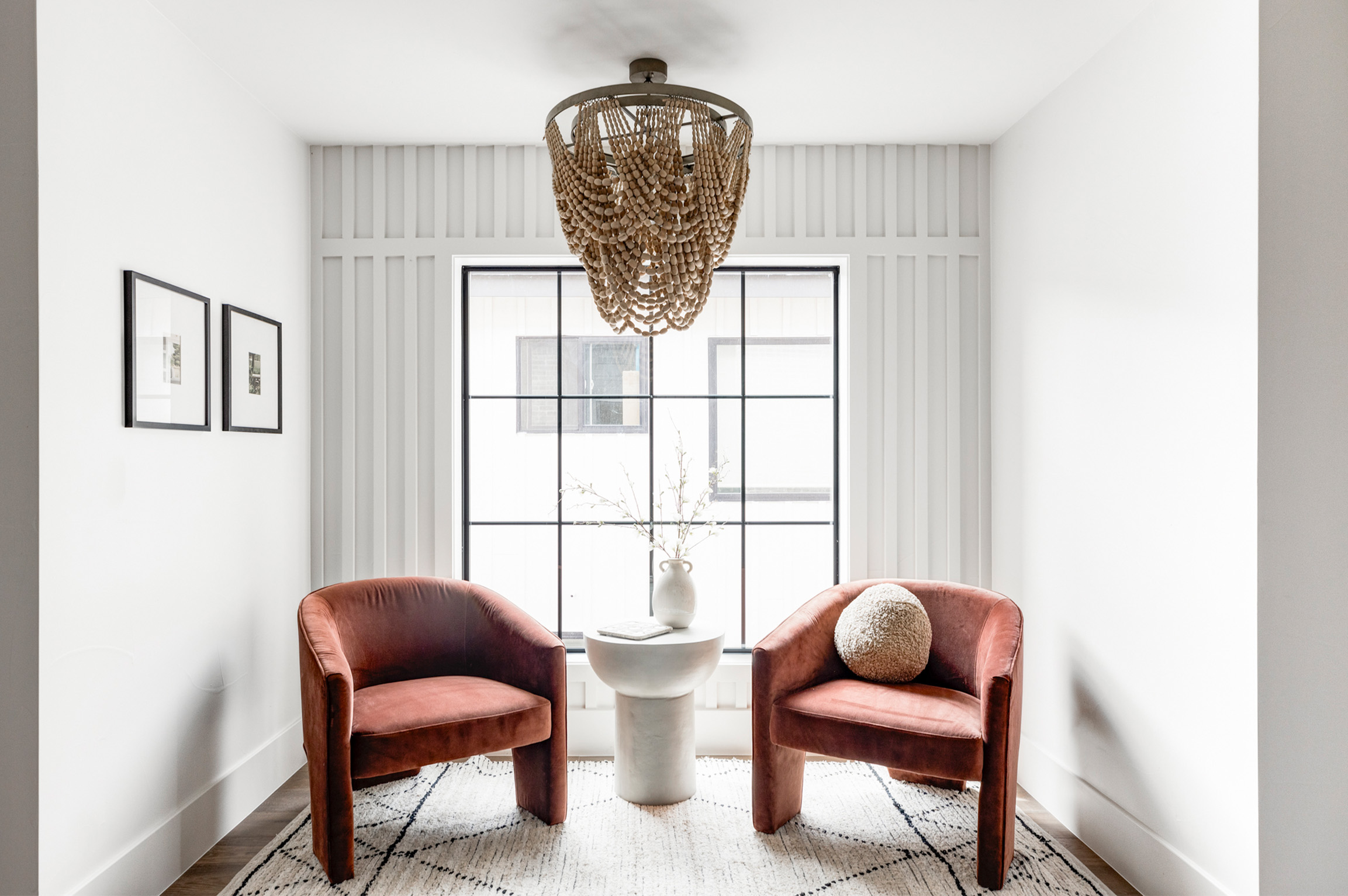Cozy sitting nook with accent chairs and statement chandelier in bright alcove.