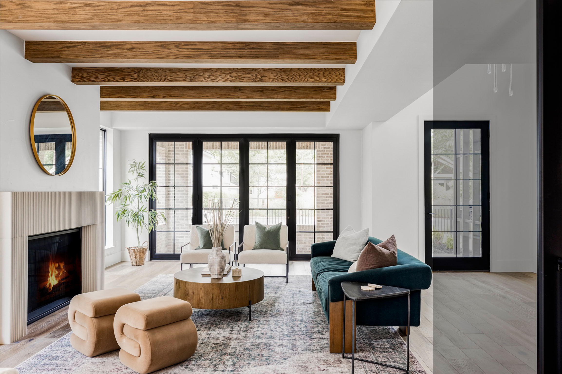 Open-concept living room with exposed wood beams and modern fireplace.