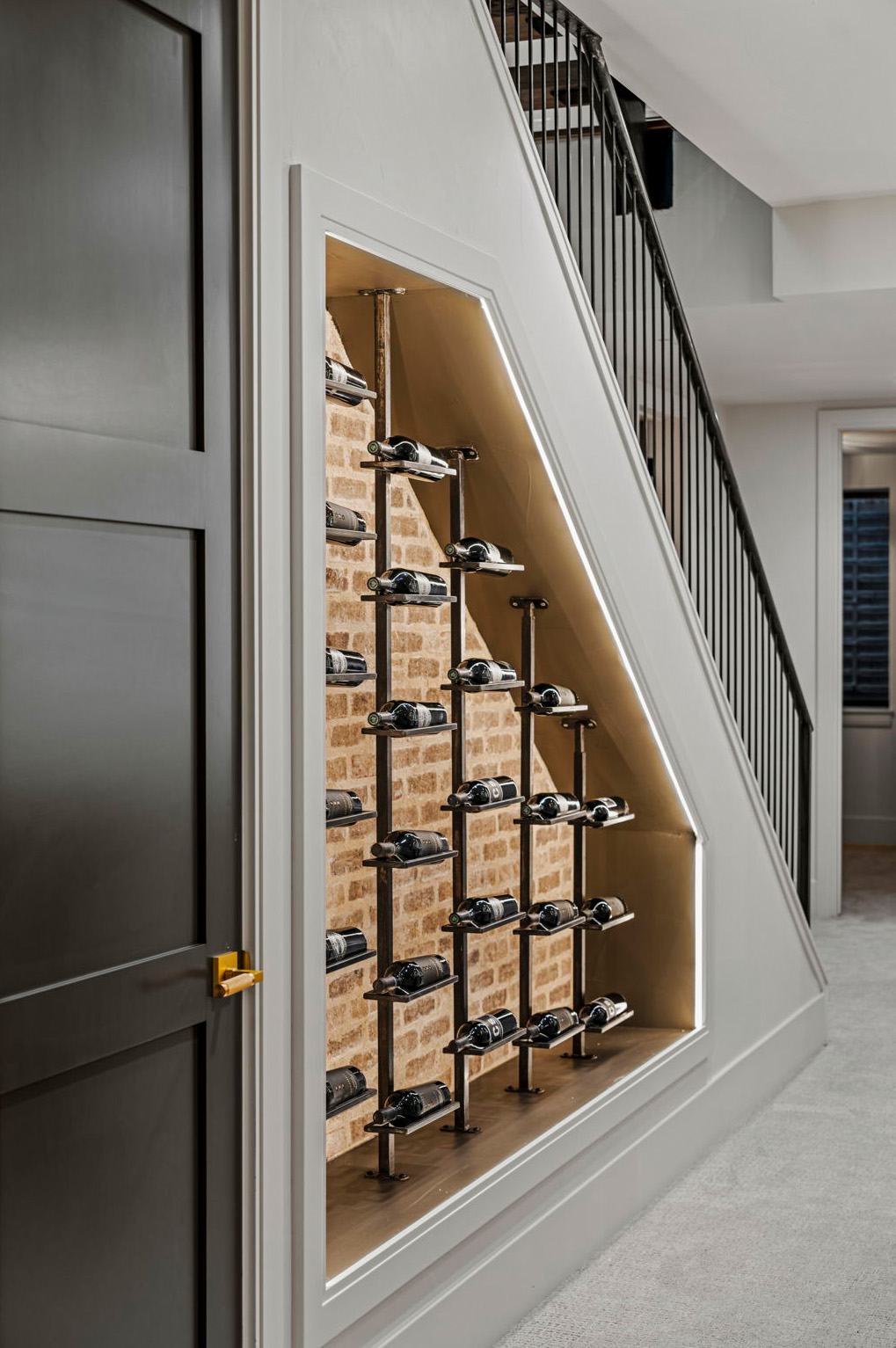 Glass-enclosed wine storage feature beneath staircase in modern luxury home.
