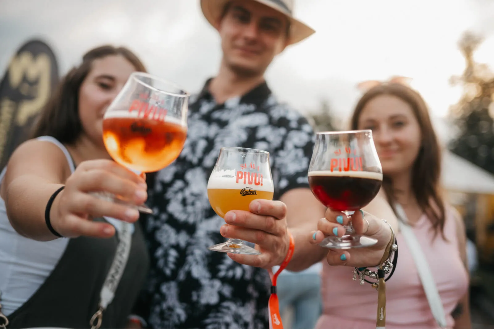 Tři lidé ukazují své sklenice piva směrem k fotoaparátu na festivalu Sláva Pivu.