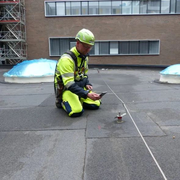 Mand der sidder på tag med faldsikring