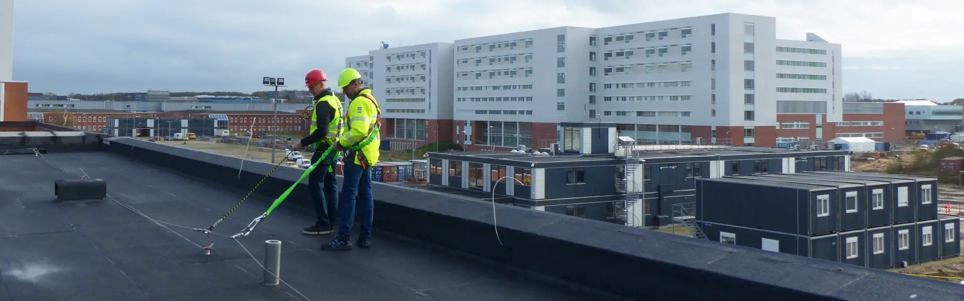 Two people wearing fall protection on a roof