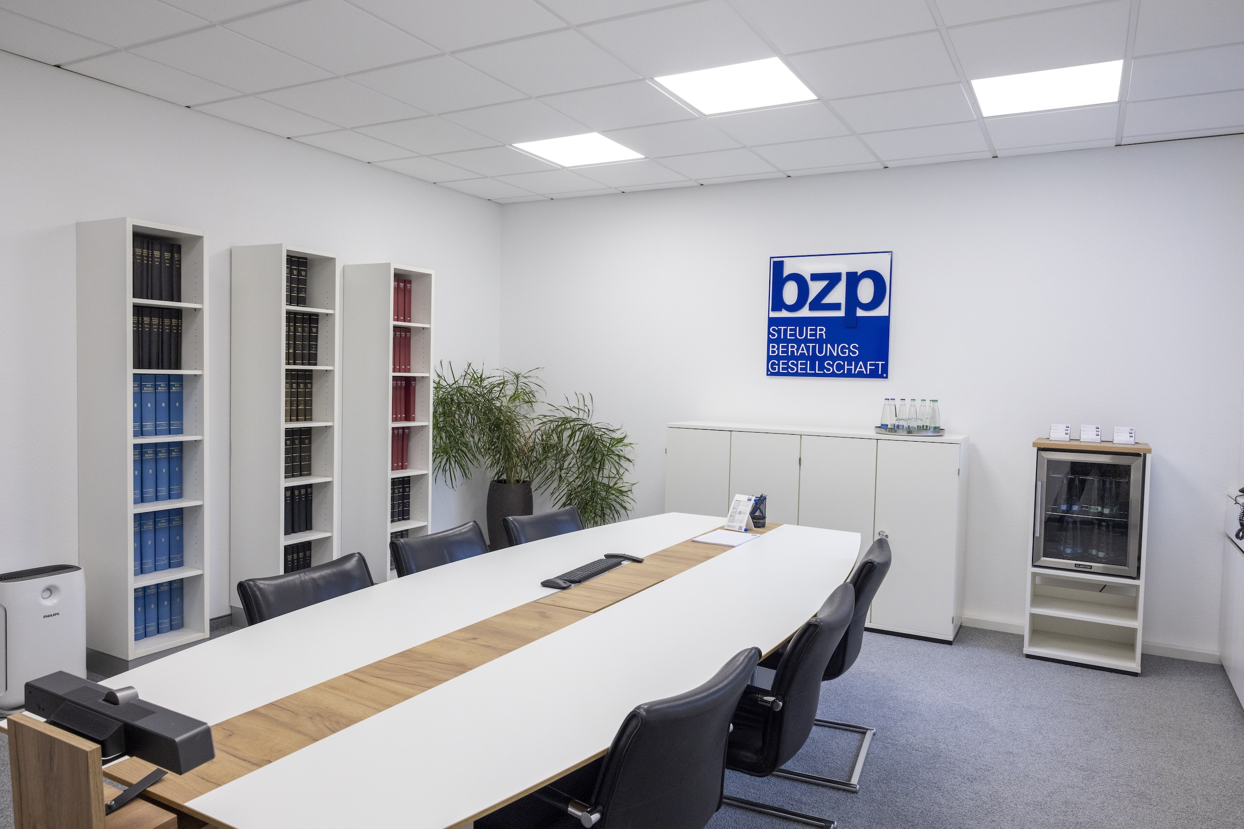 Moderner Büroraum mit weißen Tischen und blauen Stühlen