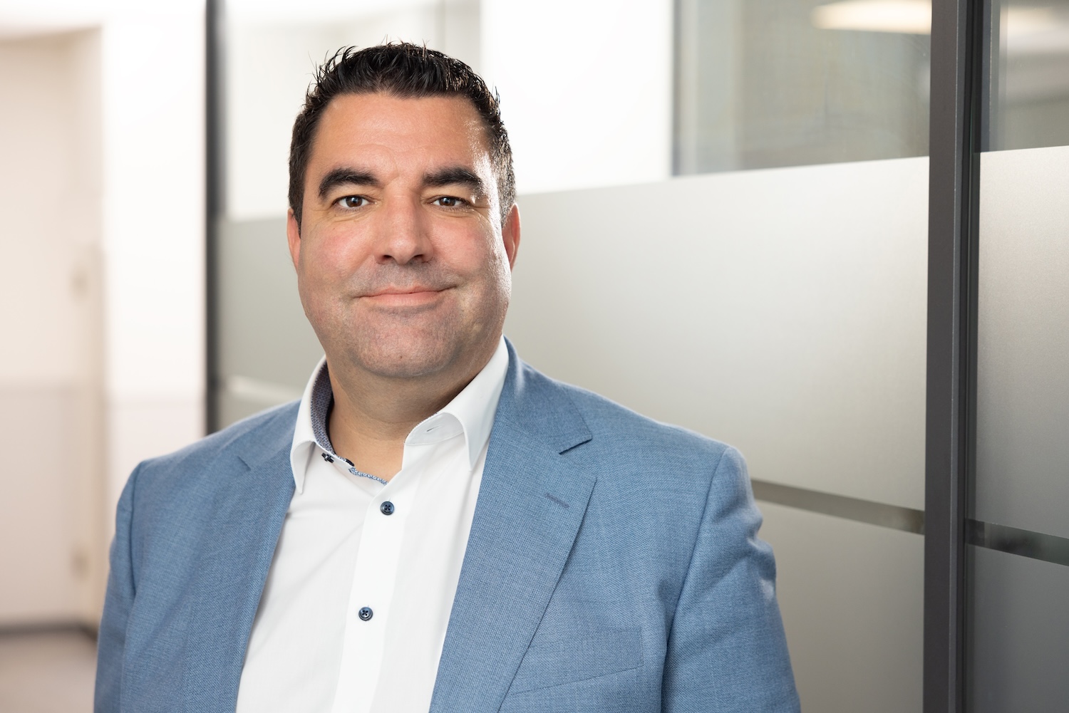 Mann mit weißem Hemd und dunklem Sakko vor hellem Hintergrund