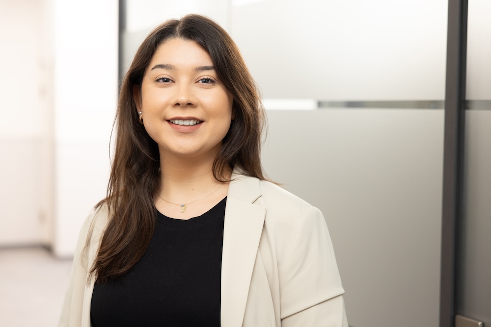 Junge Frau mit schwarzem Blazer, lächelt in hellem Raum