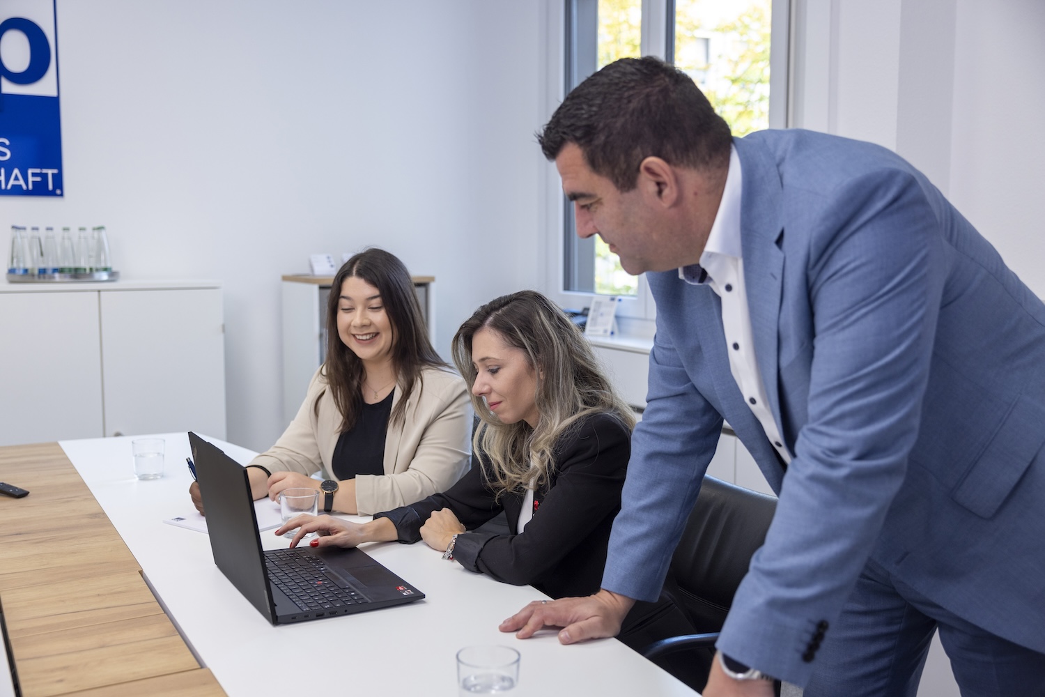 Besprechung am Konferenztisch, Mann erklärt am Laptop