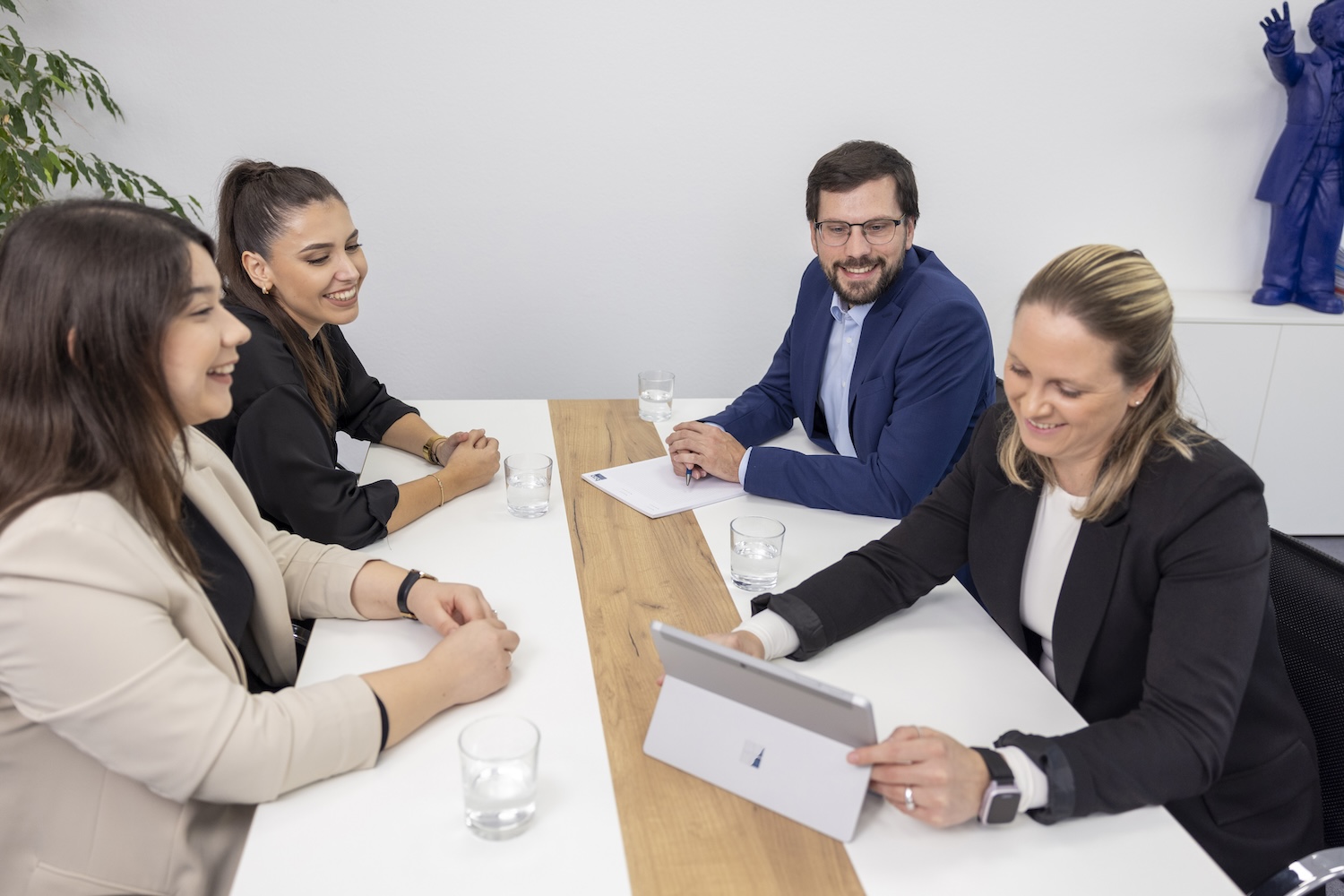 Businessmeeting mit vier Personen an Tisch, Blick zur Kamera
