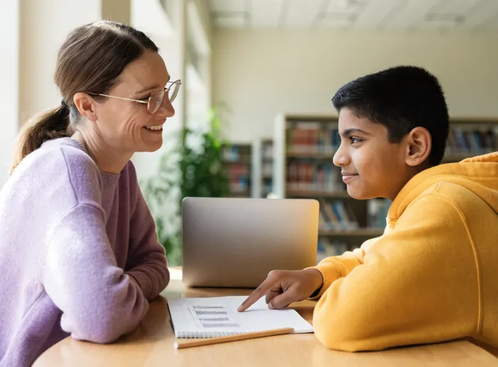A teacher and a student working together on a laptop