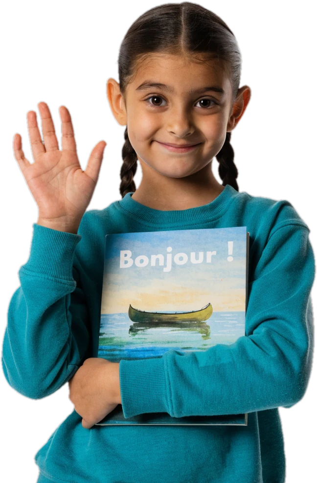 Smiling girl waving hello while hugging a French book titled Bonjour