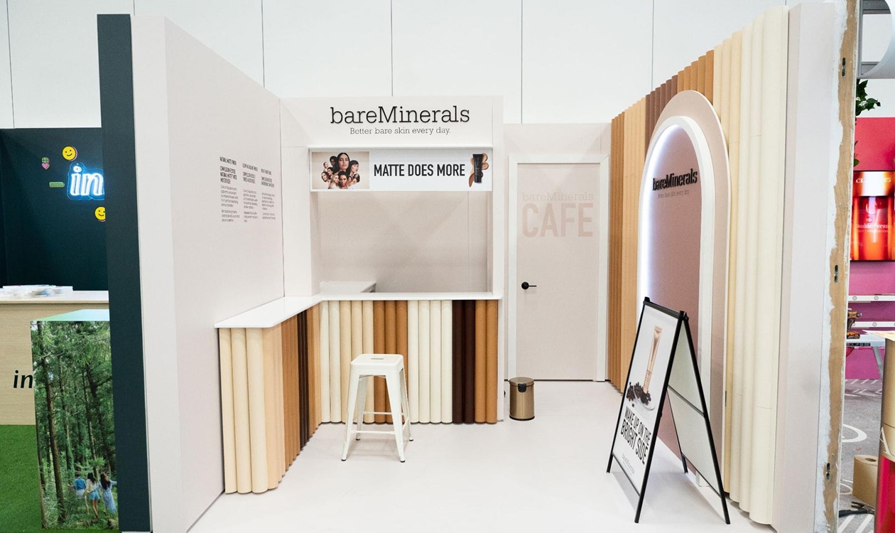 A white a brown/cream-themed booth with a table and stool sandwiched by two others. 