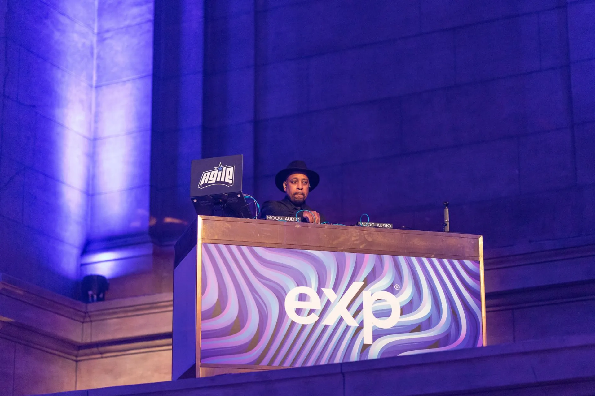 DJ in a hat playing his set behind a booth