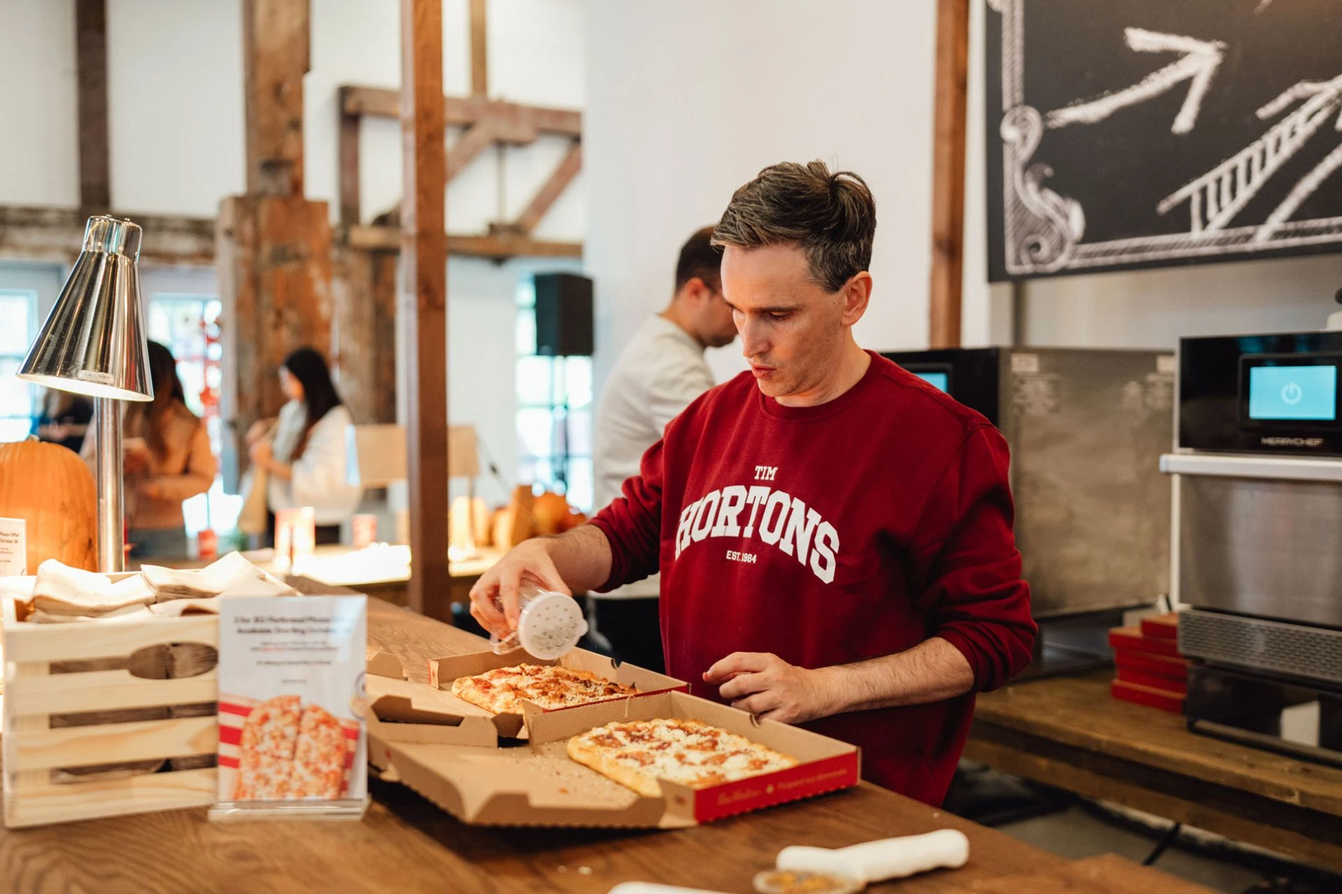 Guy in a Tim Hortons shirt making pizza