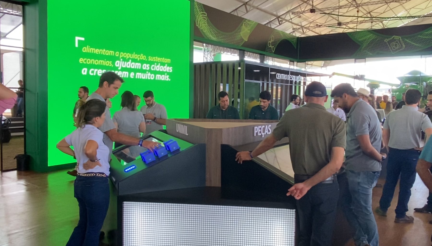 Estacao da John Deere na Agrishow com tres Mesas Cubos agrupadas e publico em volta
