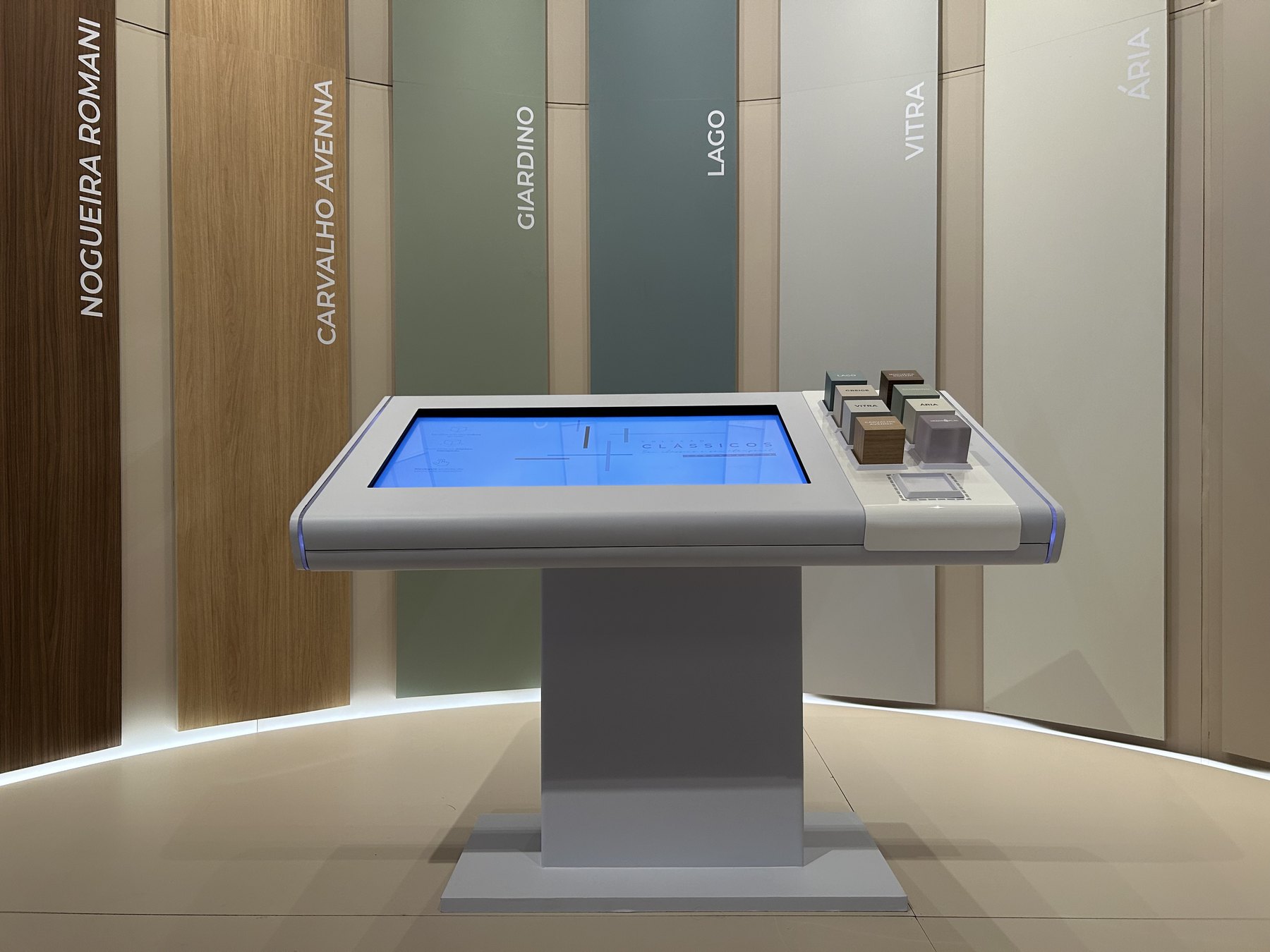 Mesa Cubos branca da Greenplac diante do painel curvo com tiras verticais de amostras de MDF