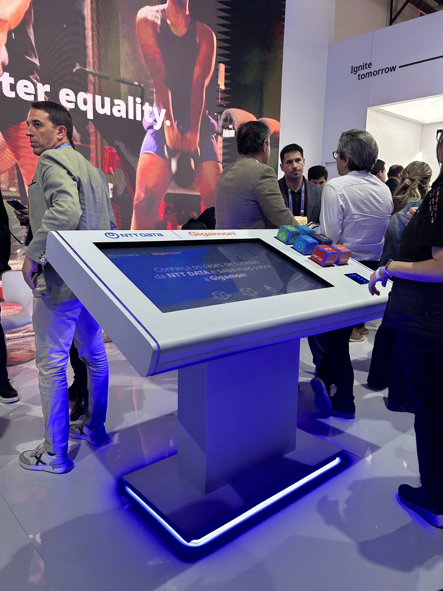 Mesa Cubos branca da NTT DATA em 2025, com cubos coloridos e LED azul na base