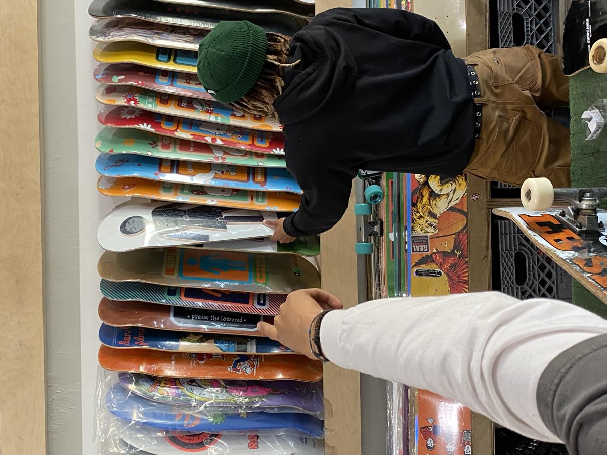 A shopper selecting a skateboard deck inside Long Beach Skate Co.