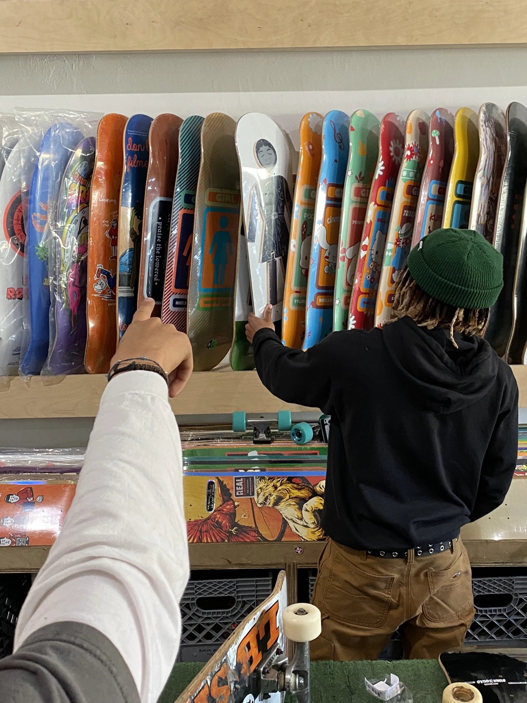 A shopper choosing a skateboard deck inside Long Beach Skate Co.