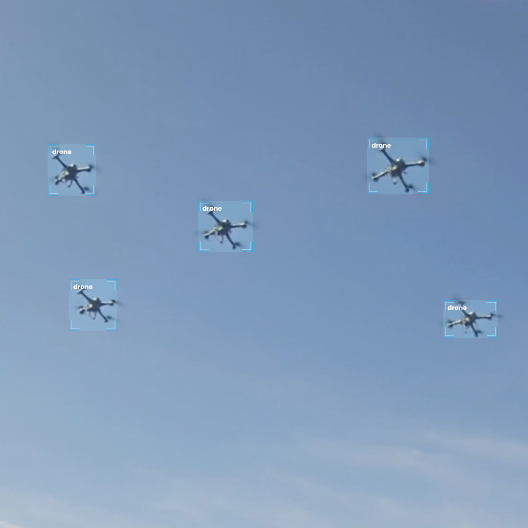 Five drones flying in a clear blue sky, evenly spaced and hovering.