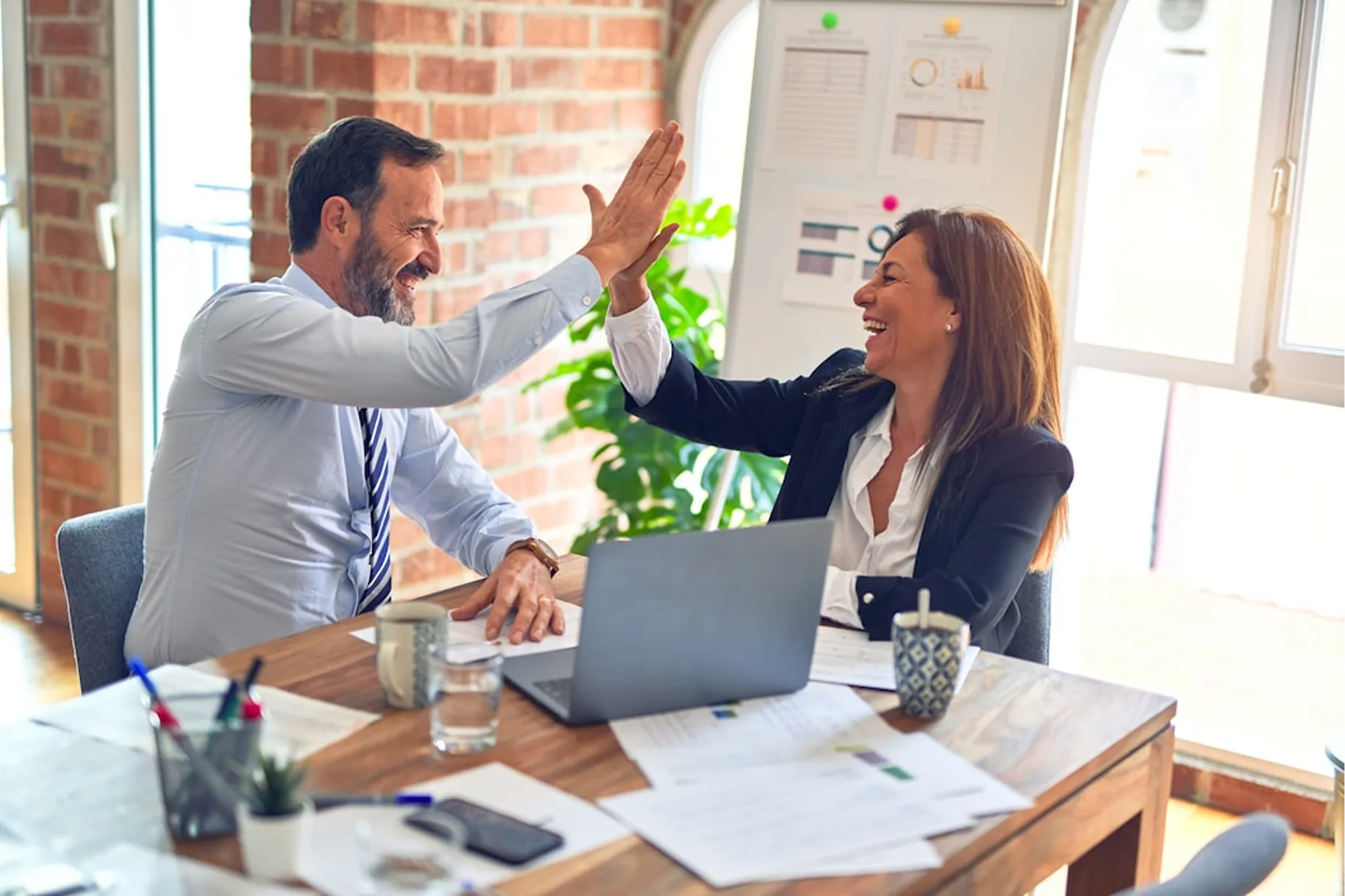A man and woman celebrating in-front of a computer 