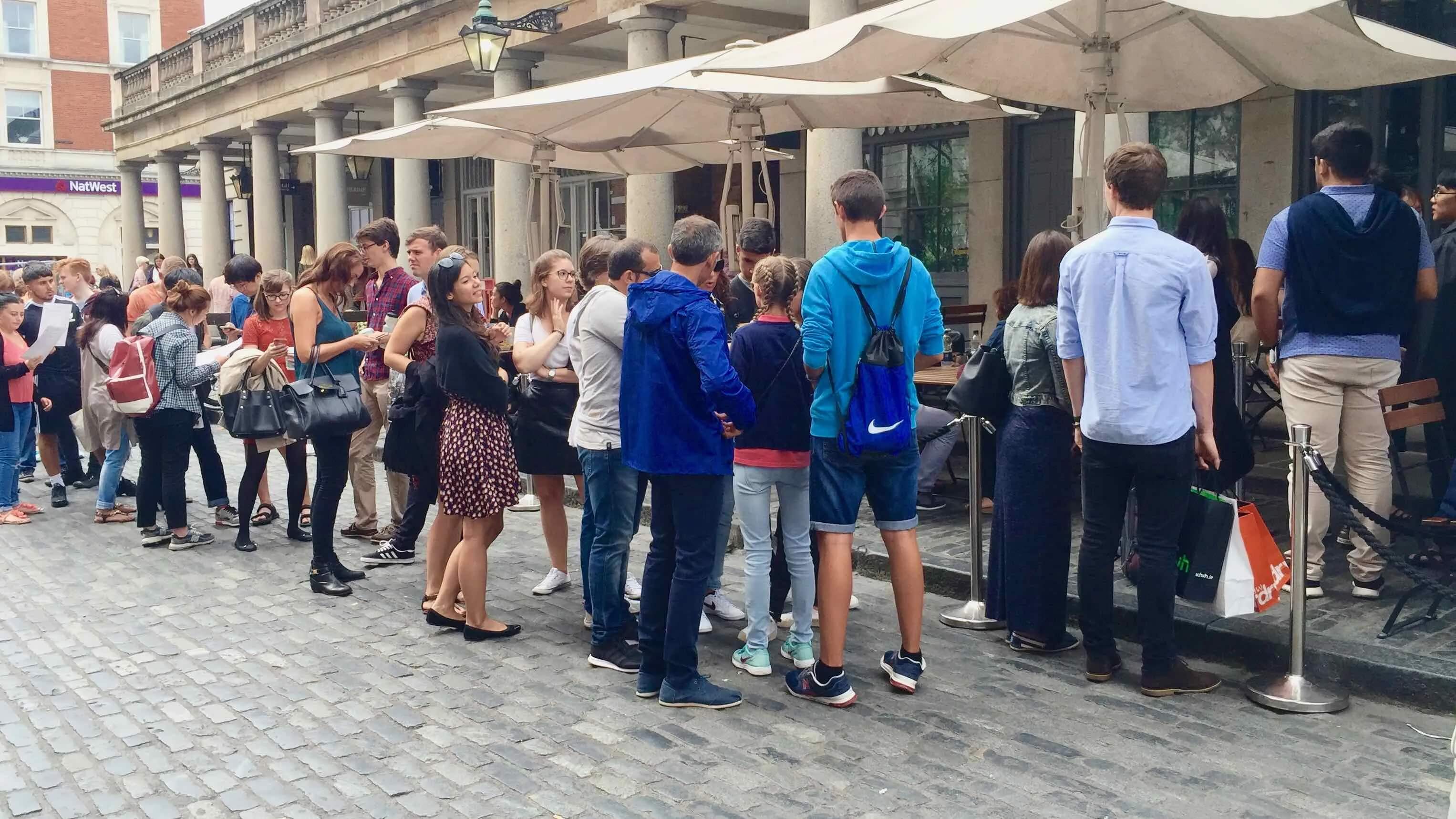 People queueing outside a café, illustrating friction and waiting in customer experience