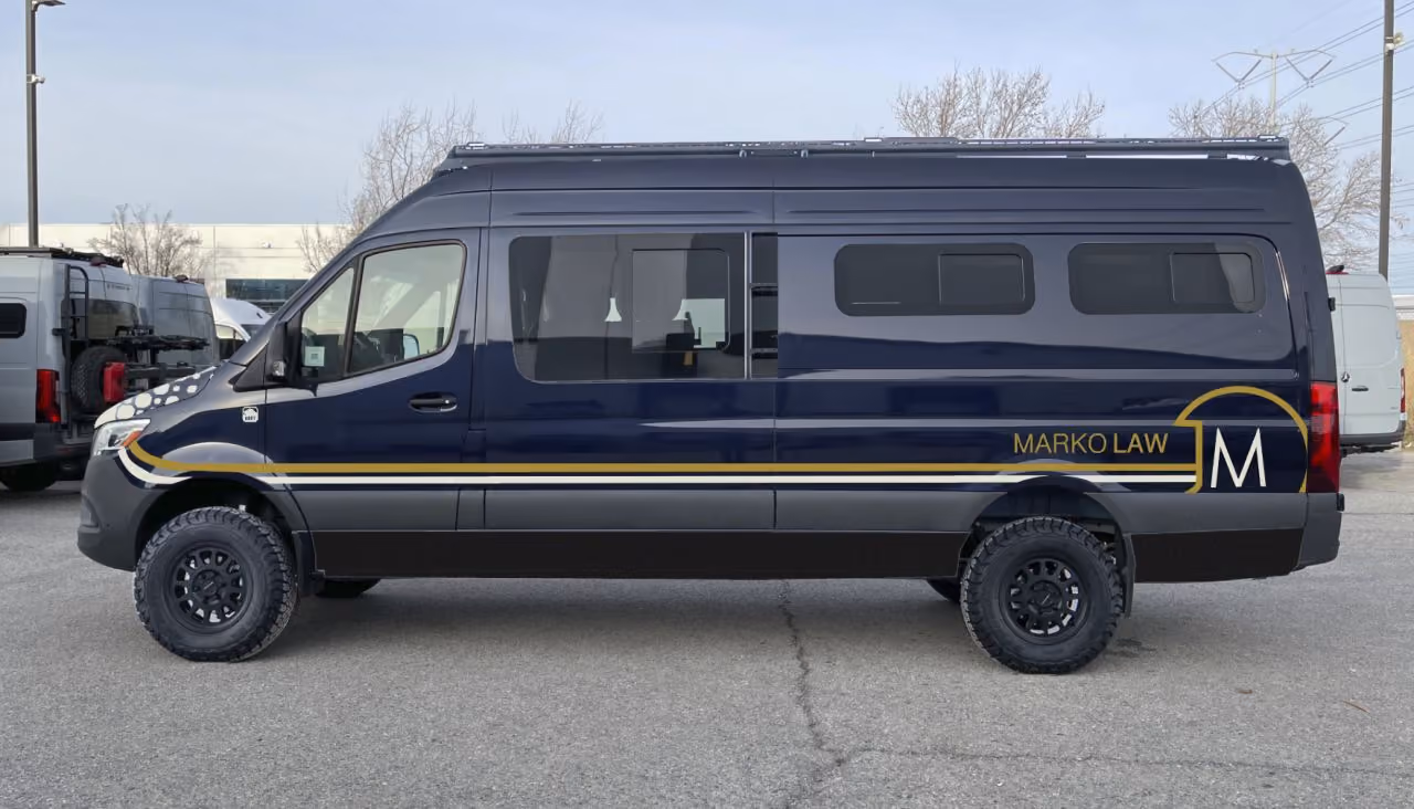 Dark blue panel van with rugged tires and the text 'Marko Law' on the side with a gold stripe.