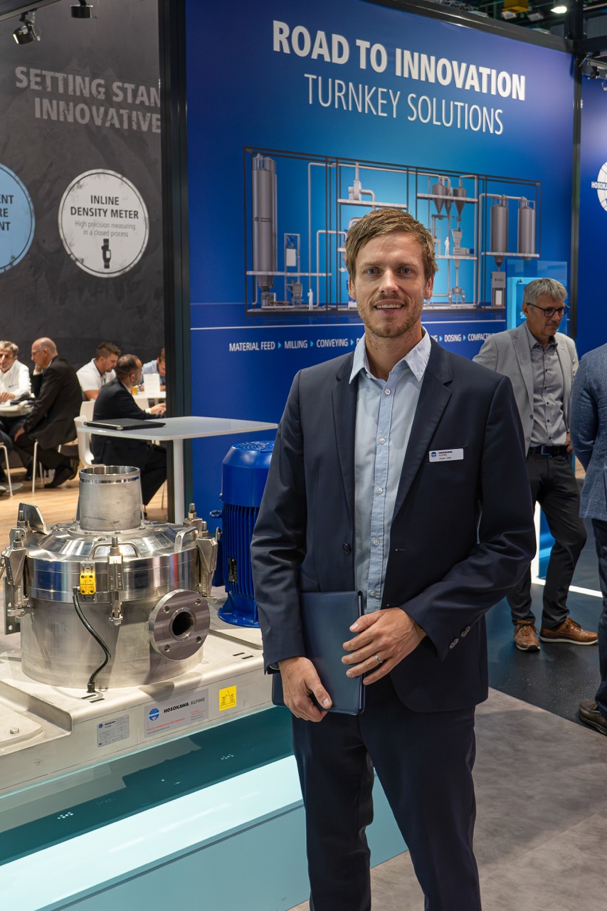 Ein Mann vor seinem Messestand